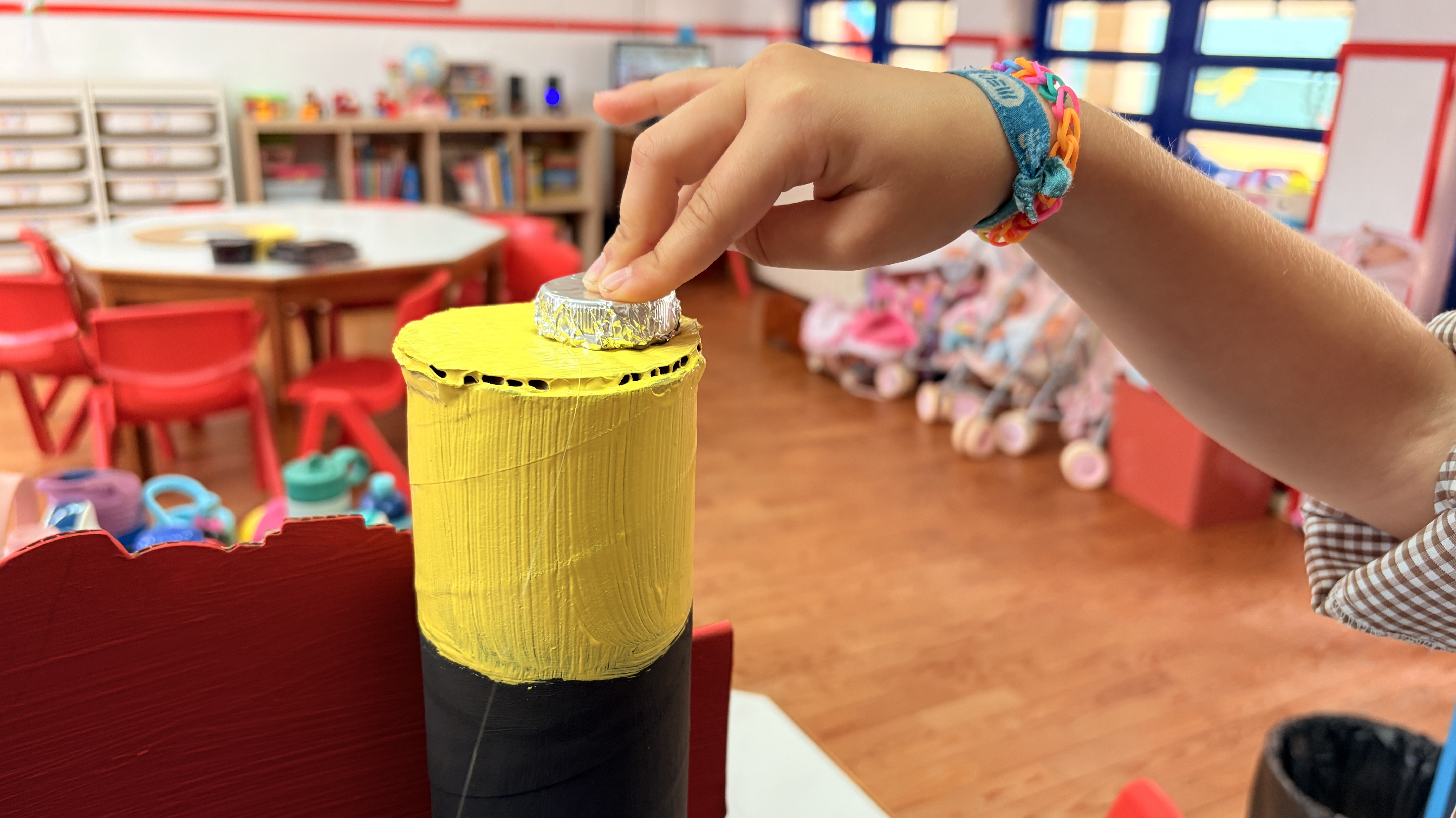 As crianças forraram com papel de alumínio e colaram tampas para simular os polos positivos da pilha