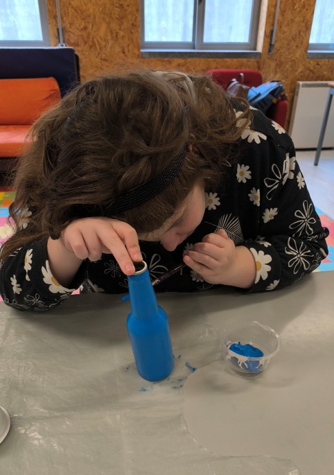 Aluna a pintar um dos copos de iogurte para fazer os olhos do “Traga Pilhas”.