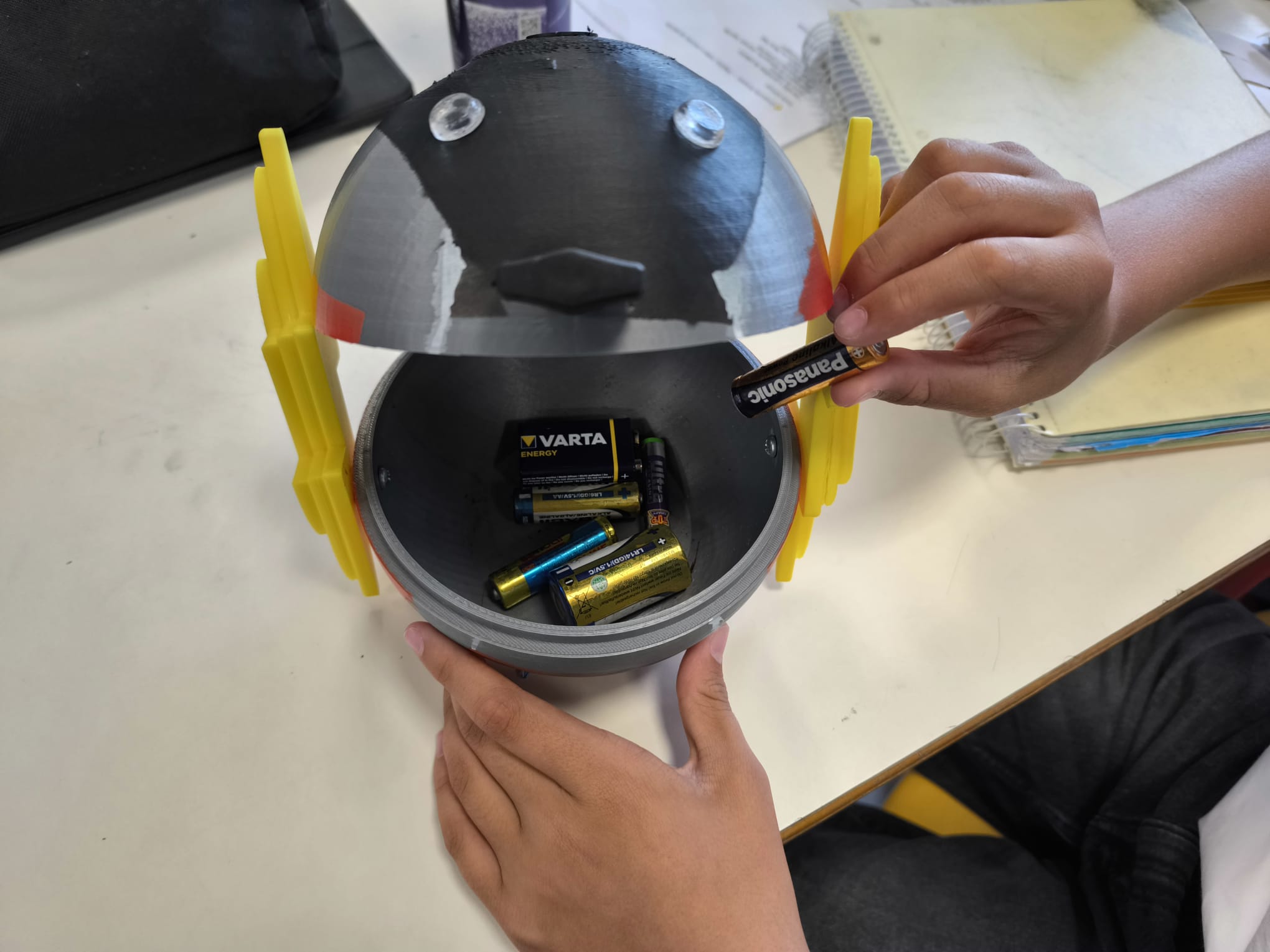 Peças produzidas por impressão 3D (estrutura principal, tampa e asas), utilizando filamento plástico reciclado, valorizando a reutilização de materiais e reduzindo a produção de resíduos.